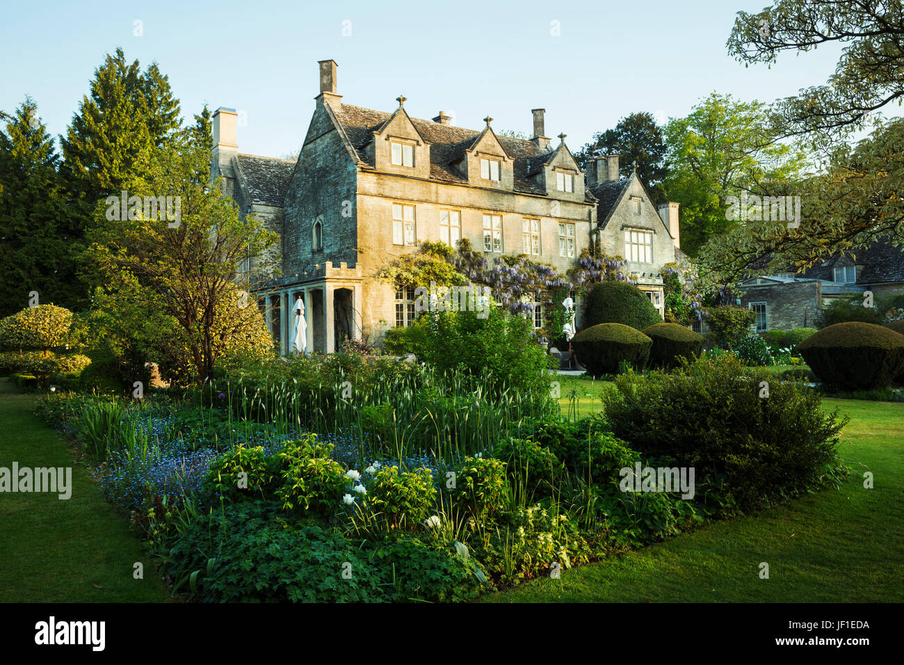 Exterior view of a 17th century country house from a garden with flower beds, shrubs and trees. Stock Photo