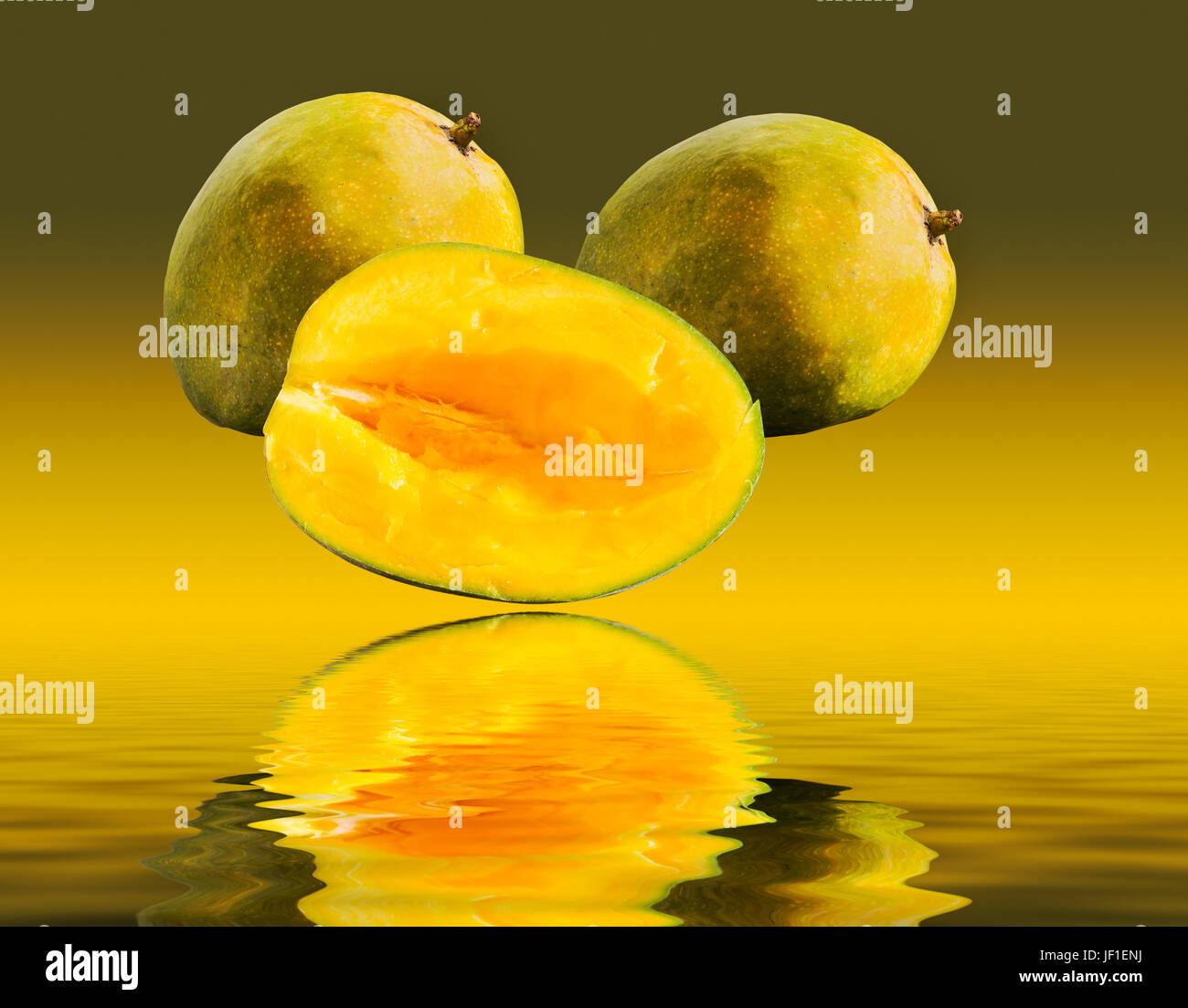 Two mangoes and one cut mango reflecting Stock Photo