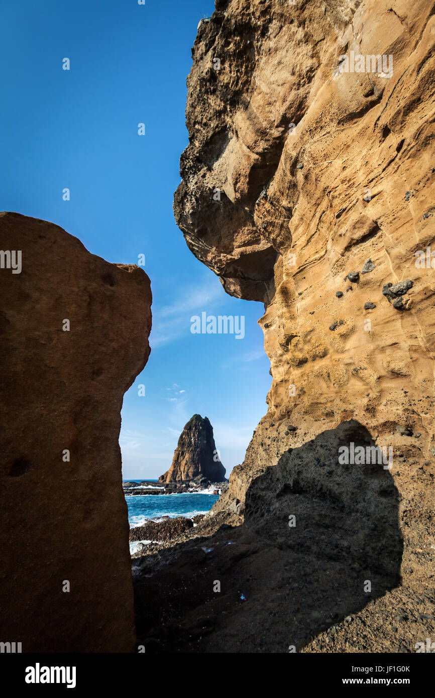Seascape of Tanjung Papuma sea stack a towering natural monument out to sea and framed with coastal eroded rocks. Astonishing geological phenomenon Stock Photo