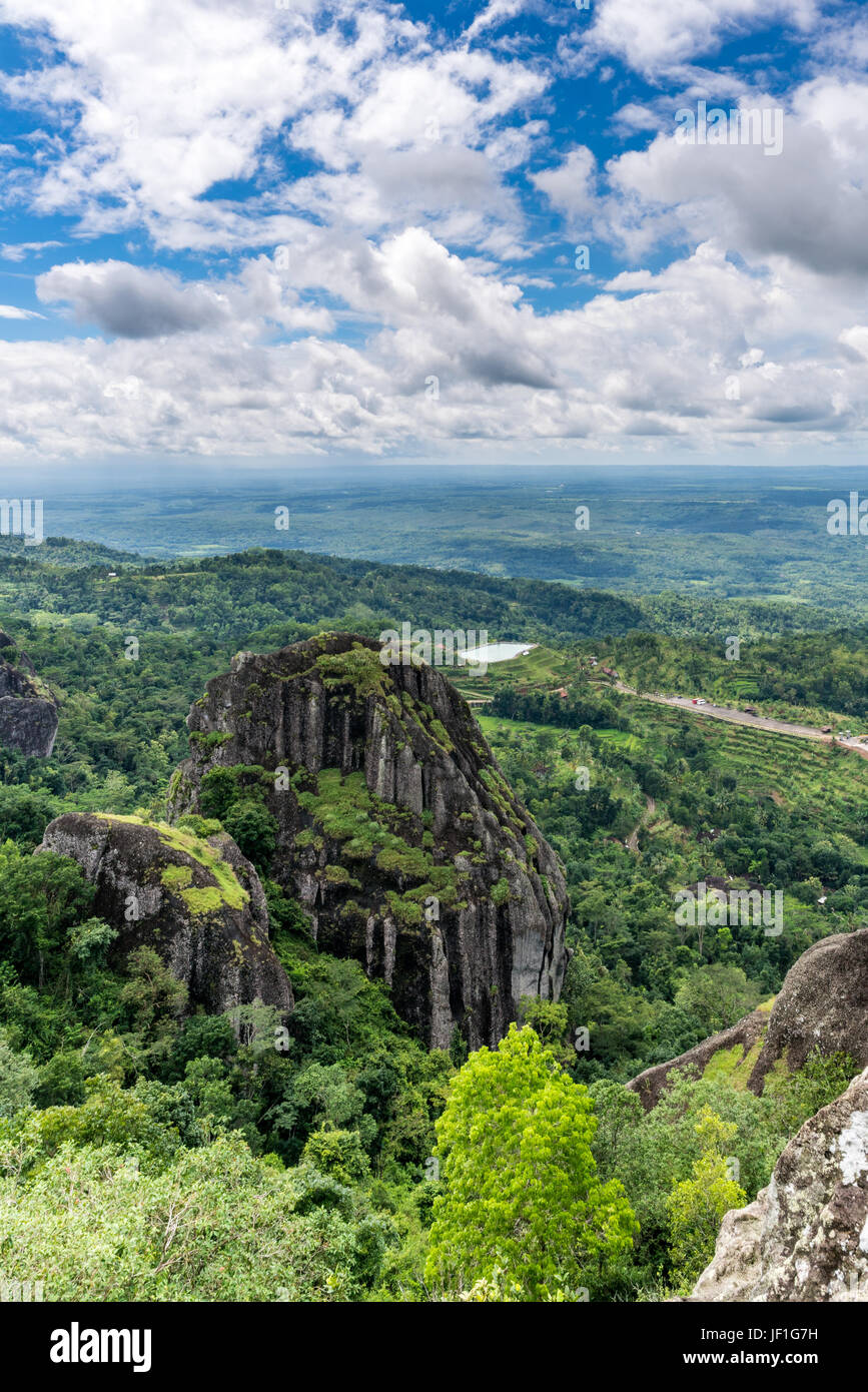 Privileged hilltop view of Indonesian countryside, with majestic rock formations and rice terraces and paddies surrounded by lush vegetation. Stock Photo
