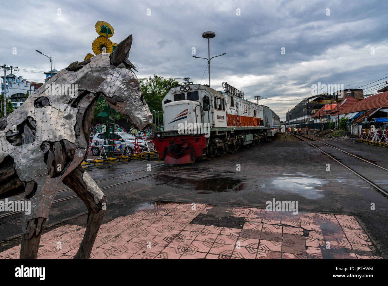 Train arriving at the Yogyakarta railway station.  View of locomotive and horse sculpture standing between the two railway tracks. Stock Photo