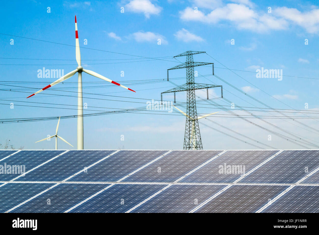 Solar panels against wind turbines. Sustainable development and renewable resources concept. Stock Photo