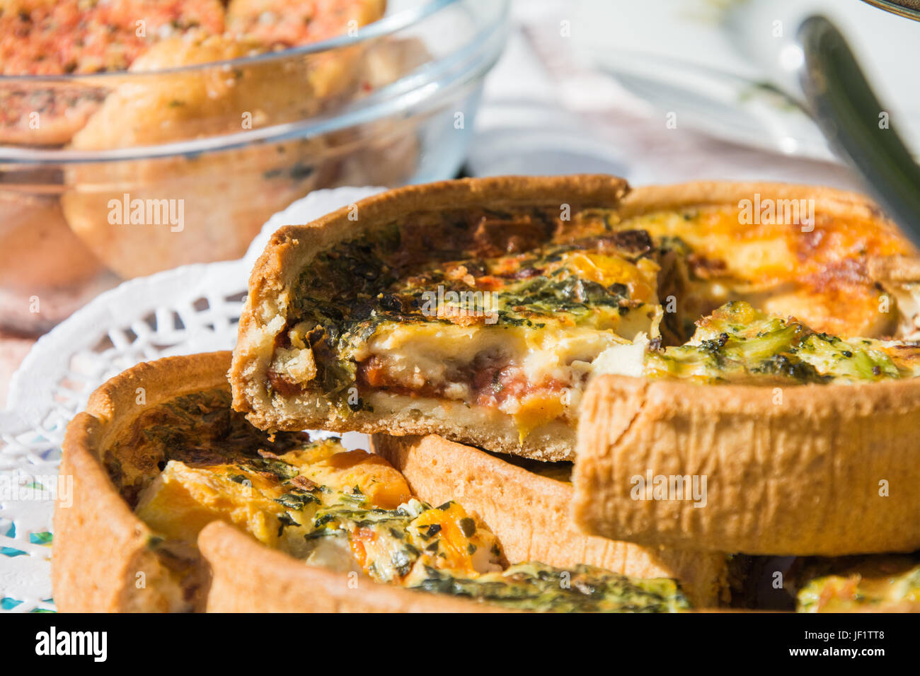 Slices of Mediterranean quiche served outdoors on a warm sunny day. Alfresco dining during an English summer. Stock Photo