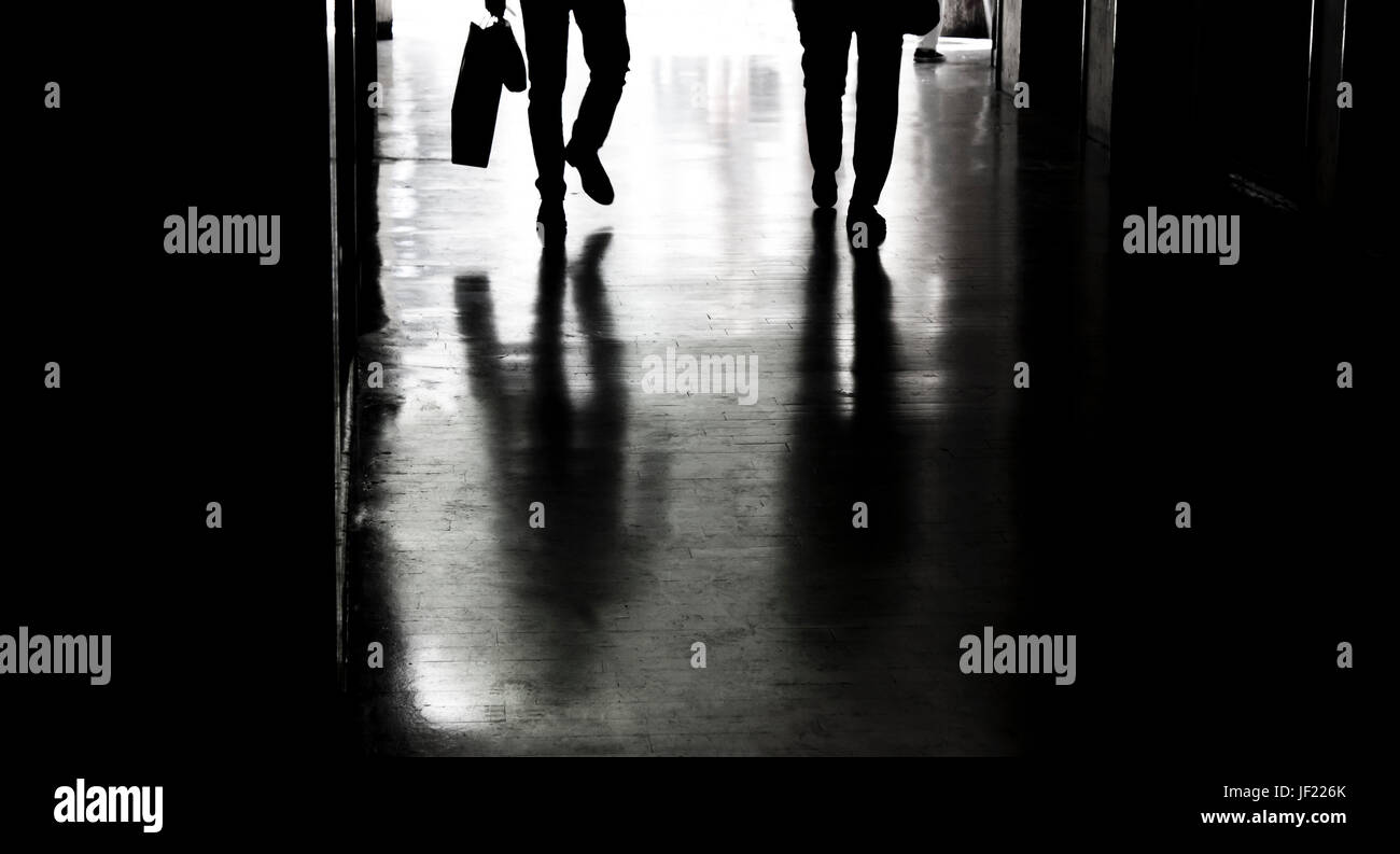 Two people silhouettes and shadows in the city passage in black and white Stock Photo