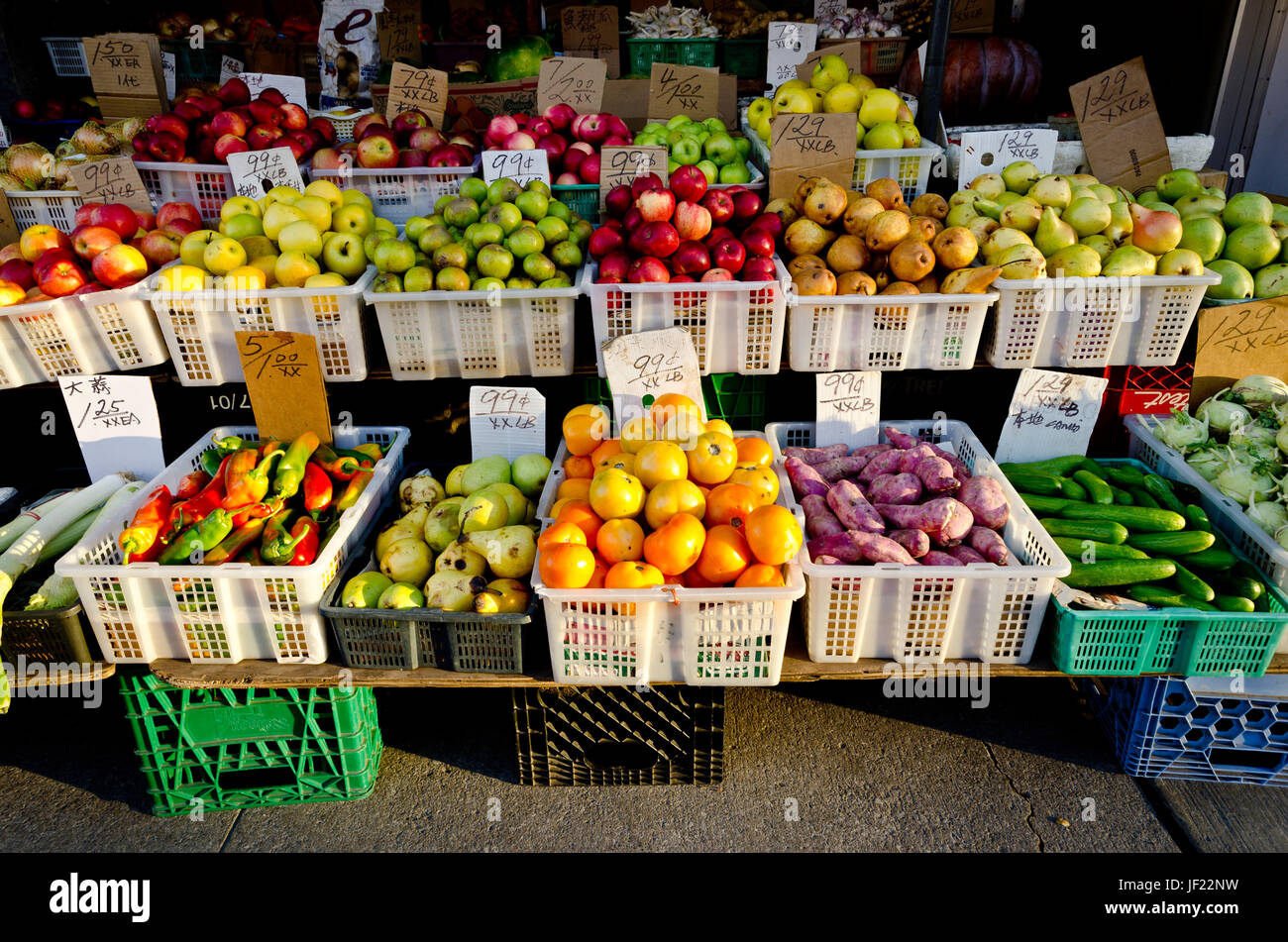 Oriental green grocer's outdoor stall showing various fruits and vegetables  in the late afternoon sun Stock Photo