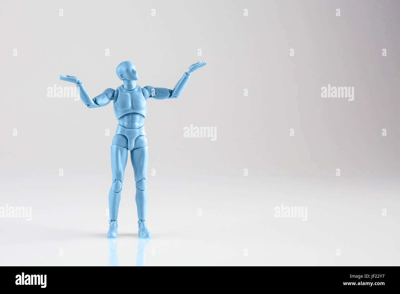 Blue male figurine standing isolated on white reflective background with both hands up. Trying to make a decision concept with copy space Stock Photo