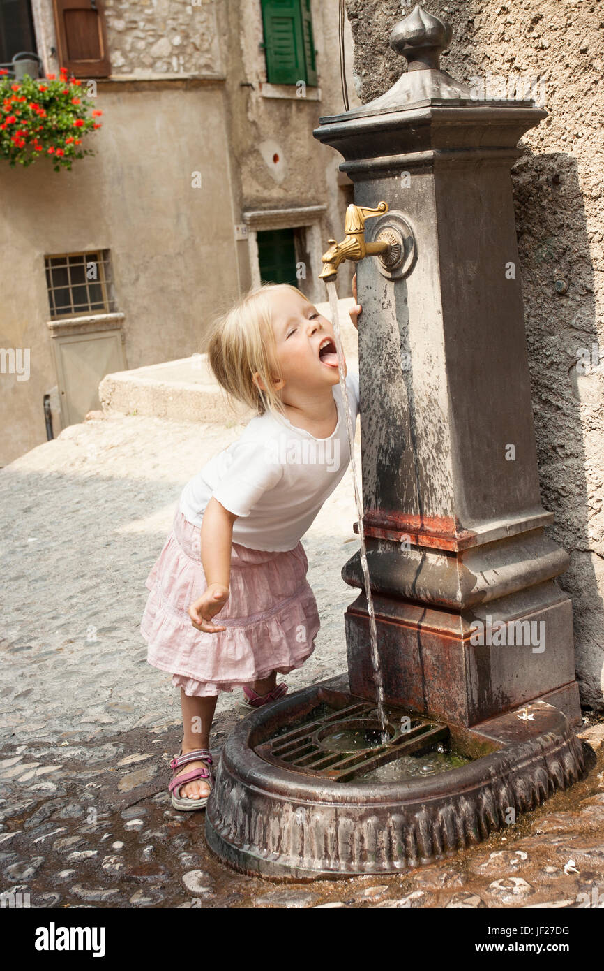 Girl drinking water from outdoor tap Stock Photo