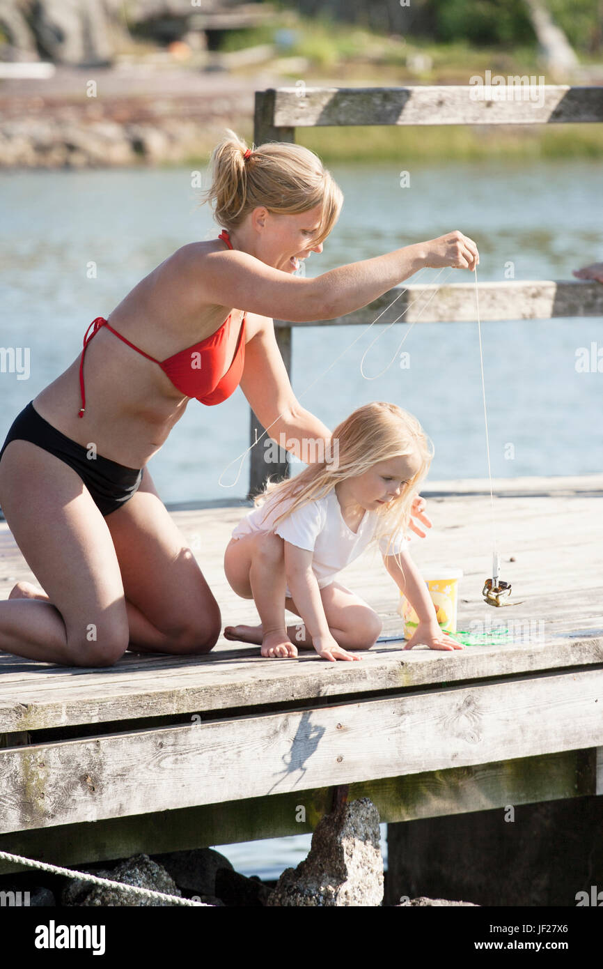 Mother with daughter fishing on jetty Stock Photo