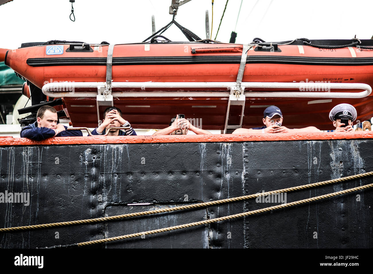 Szczecin, Poland, June 14, 2015: Sailors texting on a smartphones on a ship. Stock Photo
