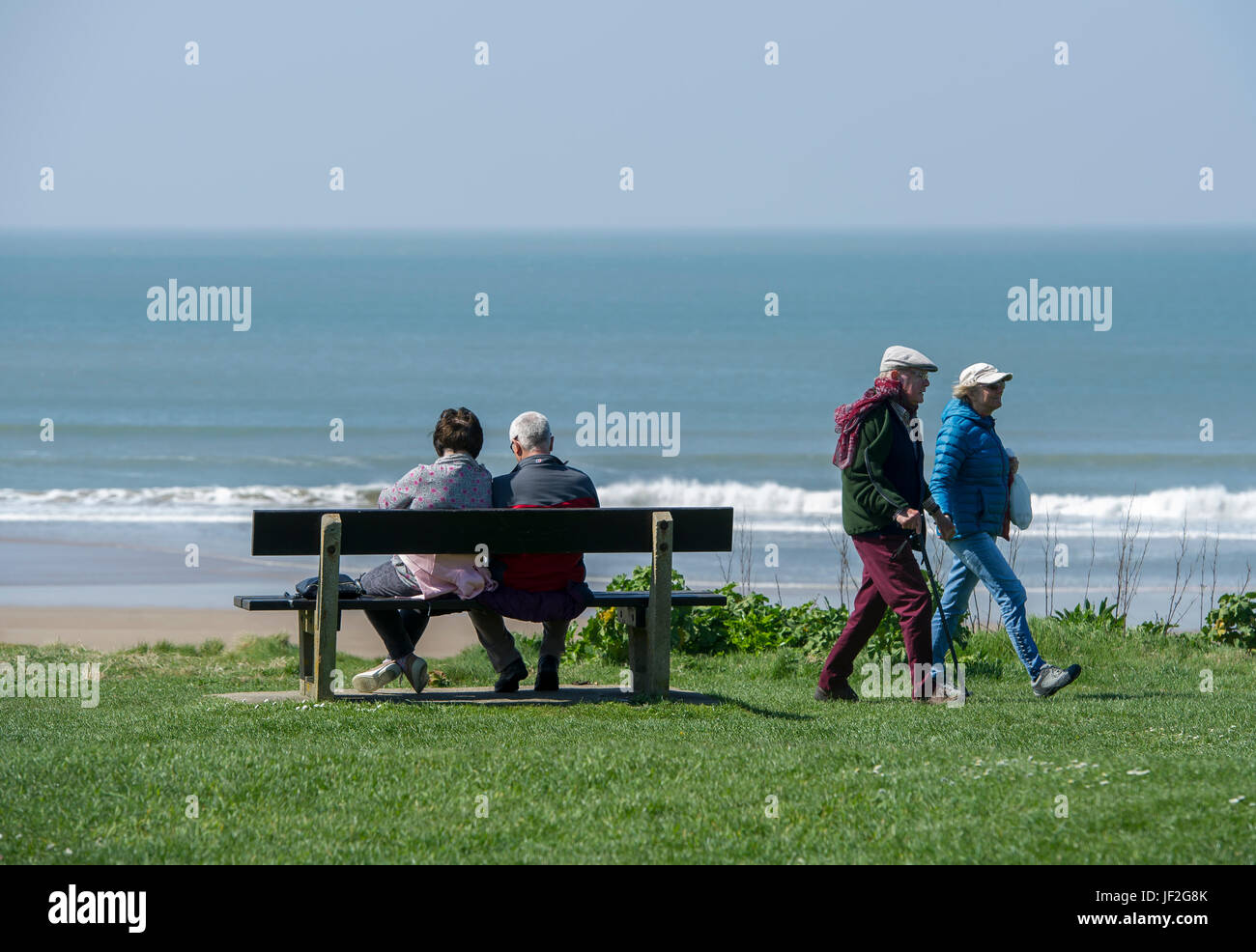 Older couple sat relaxing watching the sea at Woolacombe beach, Devon Stock Photo