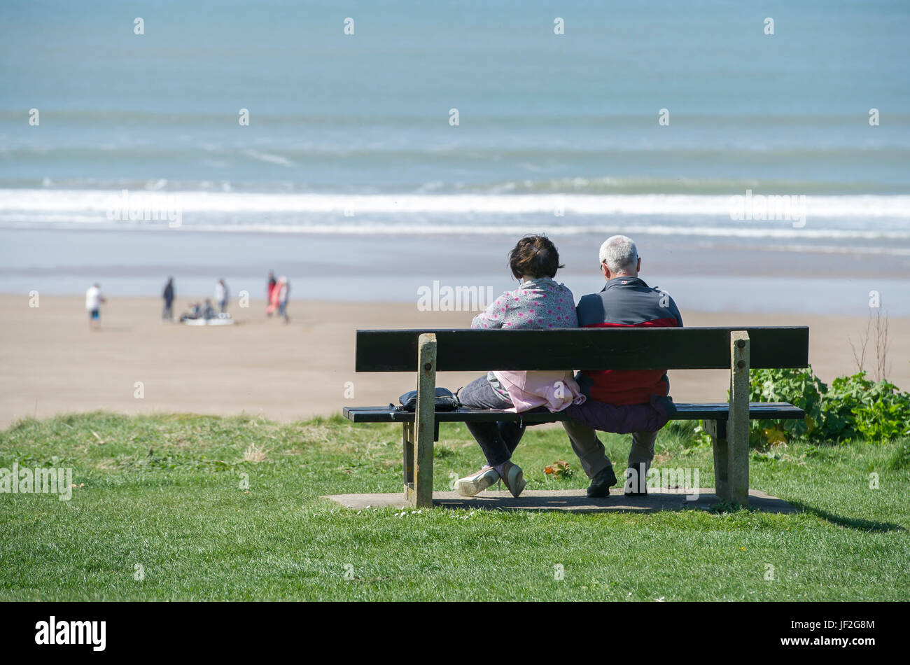 Older couple sat relaxing watching the sea at Woolacombe beach, Devon Stock Photo