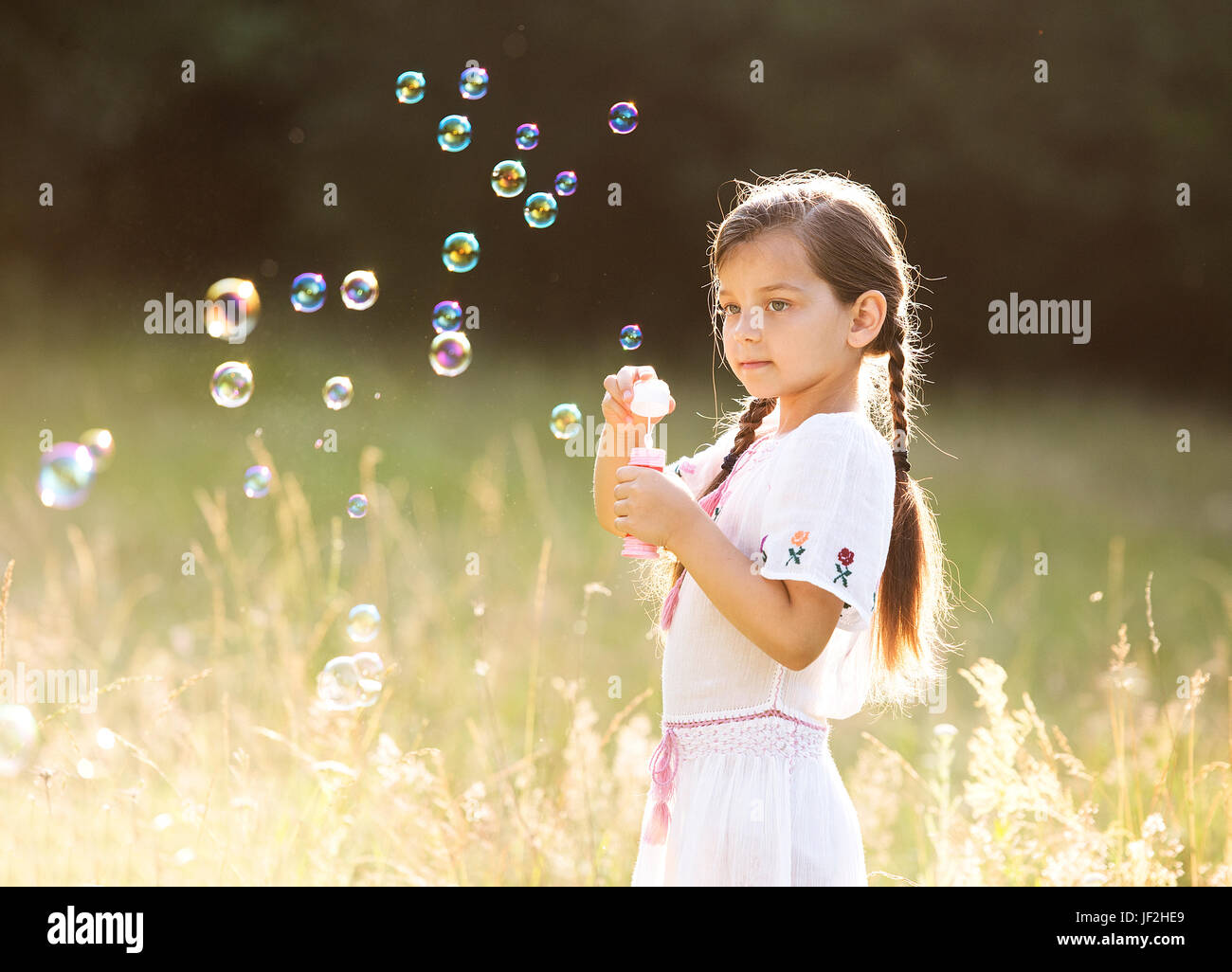 little happy girl with tight braids wearing traditional romanian blouse running outside Stock Photo
