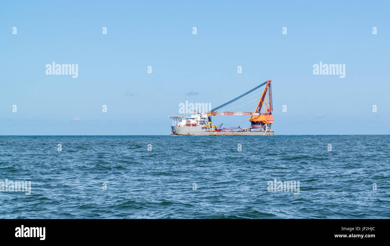 Heavy lift ship with big ship crane sailing on North Sea leaving port of Rotterdam, Netherlands Stock Photo