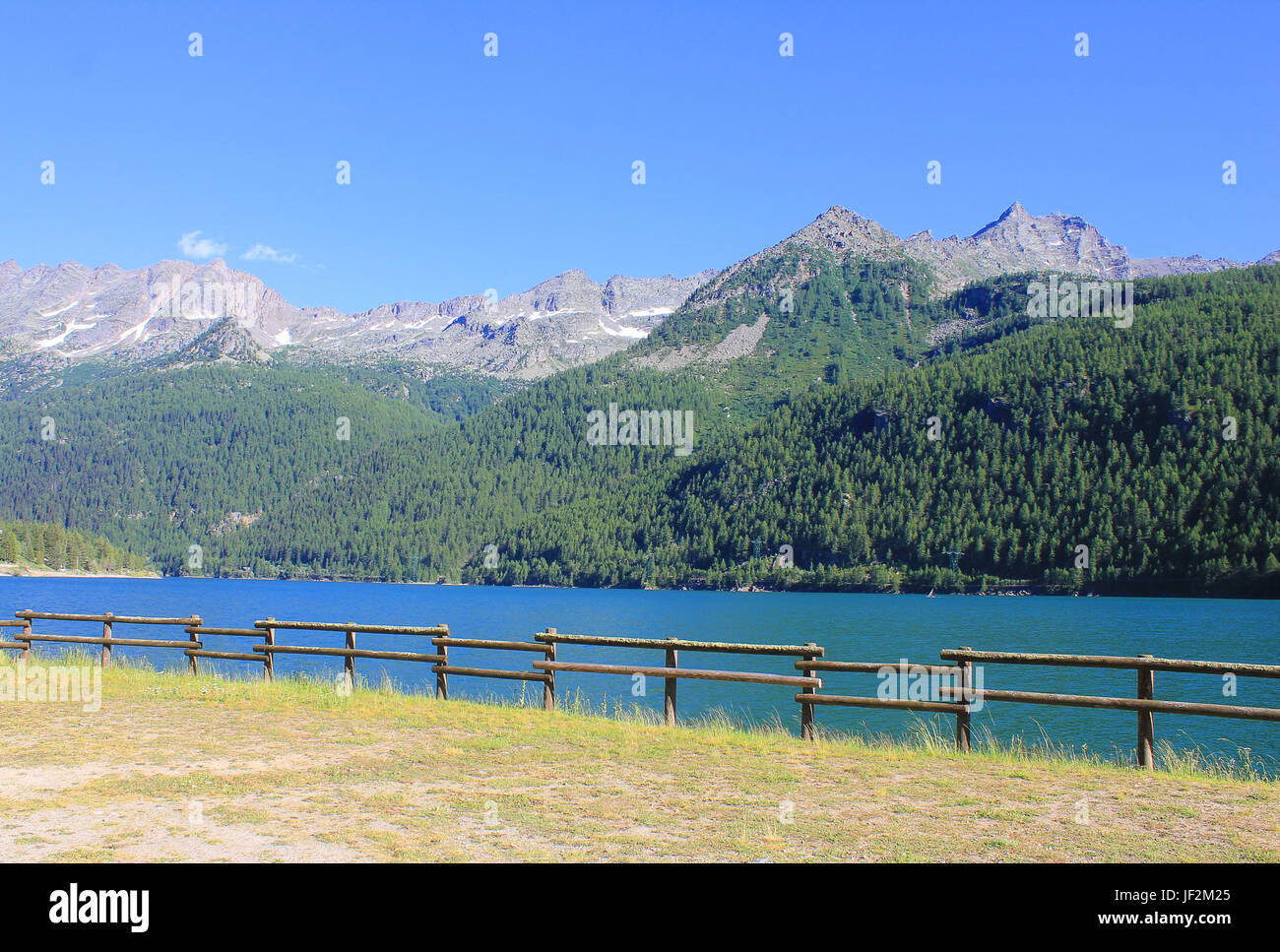 a fence around the lake in front of mountains Stock Photo - Alamy