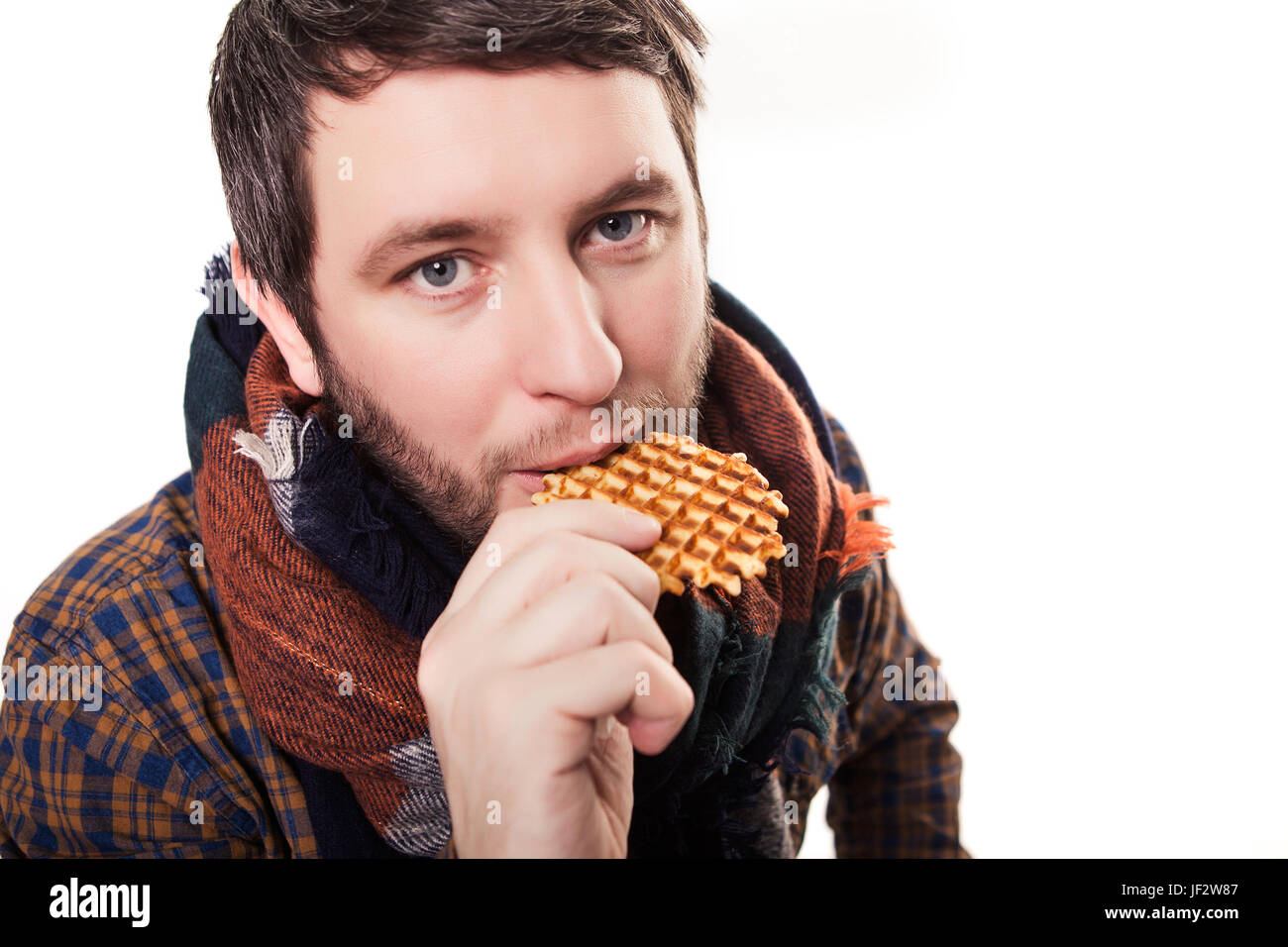 Smiling man eating a cookie and holding a jar full of cookies isolated