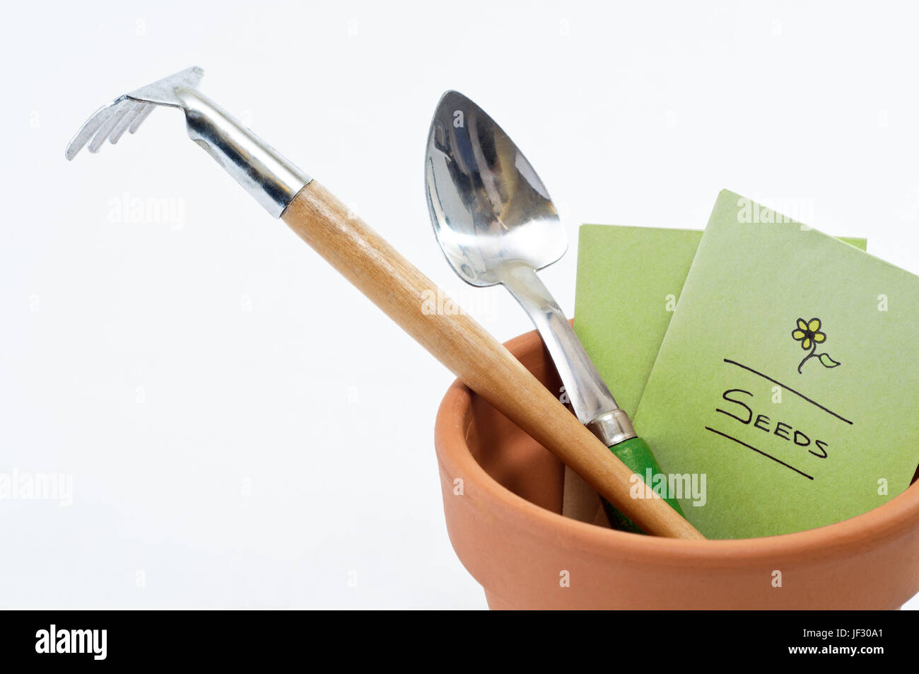 Close up of a terracotta plant pot containing seed packet and potting