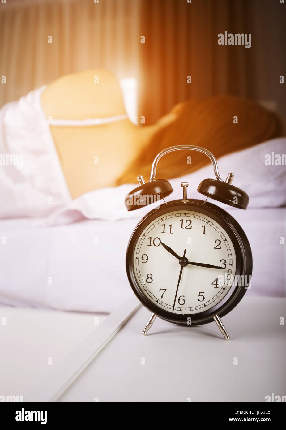 clock show 10 am. and woman sleeping on bed with sunlight in the