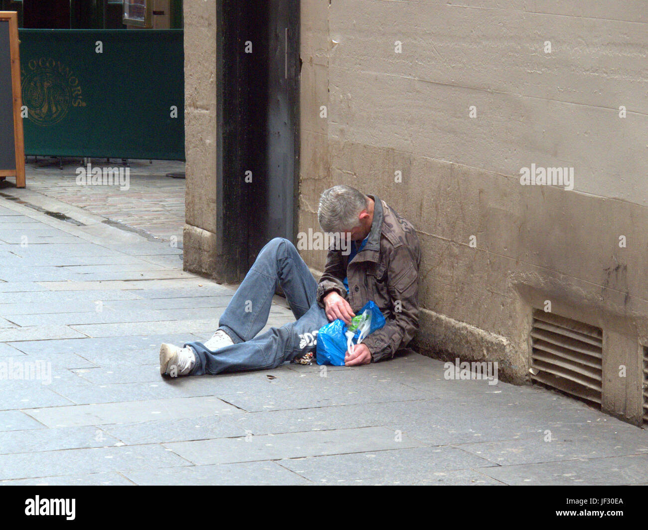 zombie drug spice begging homeless unemployed man lying  on the street unconscious Stock Photo