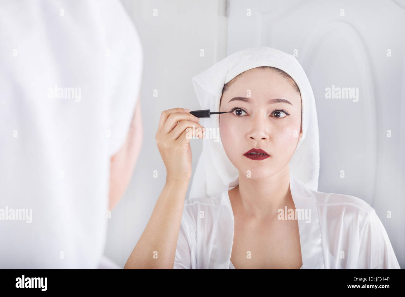 Beautiful woman looking mirror and make-up with black eyeliner Stock Photo