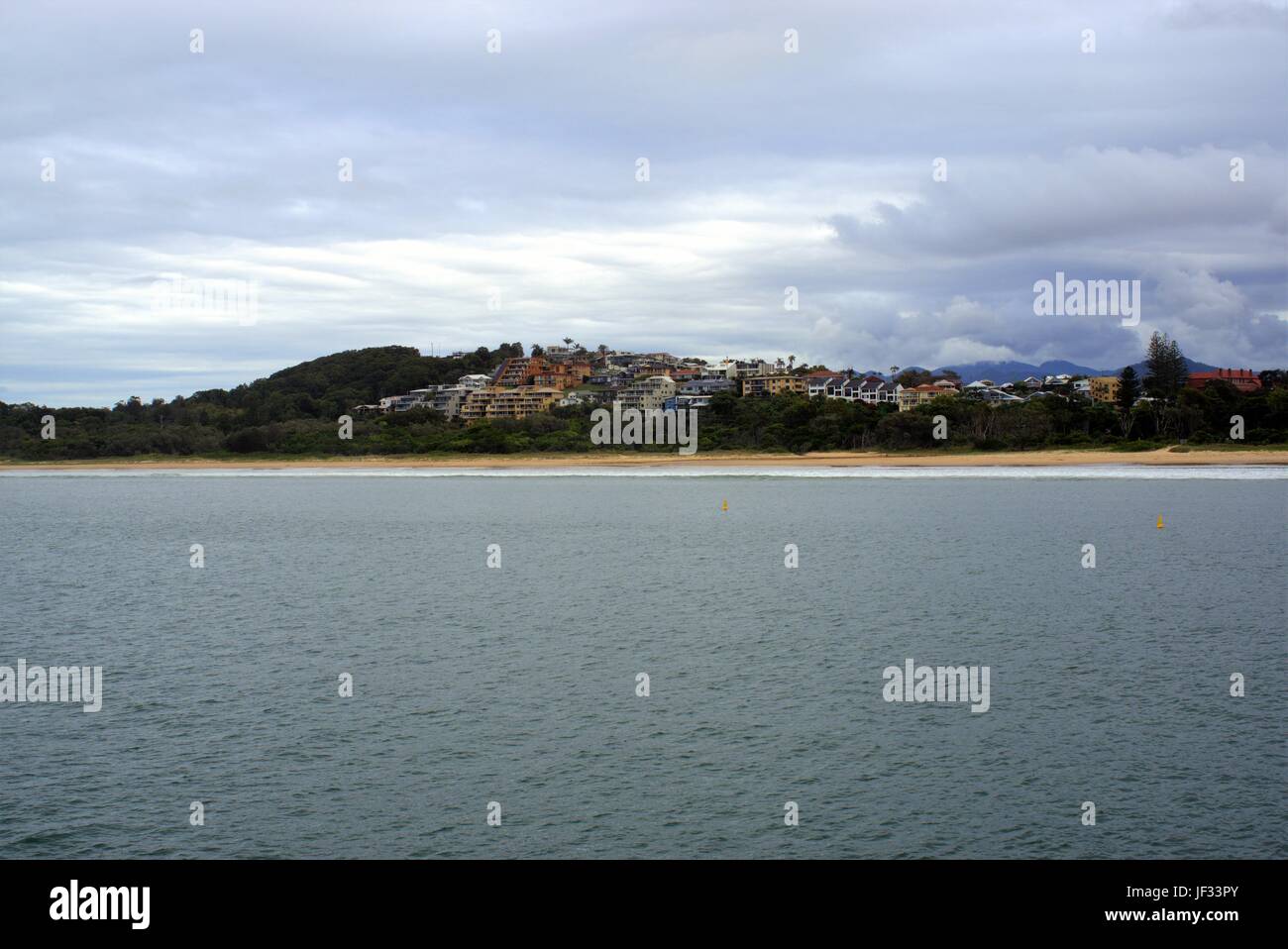 View of island from a beach in Australia and beachfront houses out far in the distance. Sea facing homes at Jetty beach, Coffs Harbour. Stock Photo