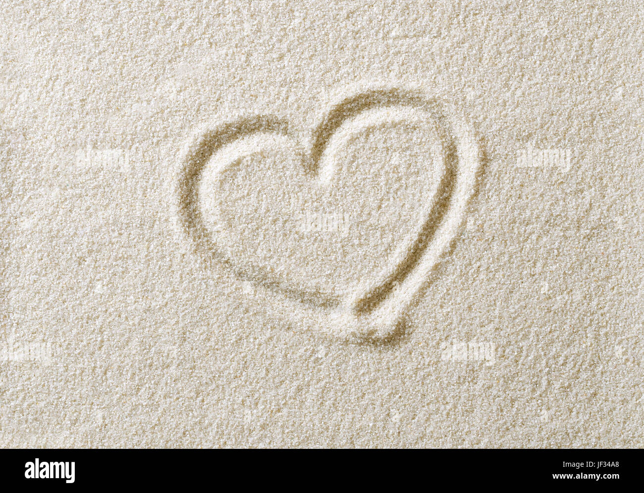 Heart symbol drawn in sand surface. Heart shape, an ideograph to express emotion like romantic love. Metaphoric. Macro photo close up from above. Stock Photo