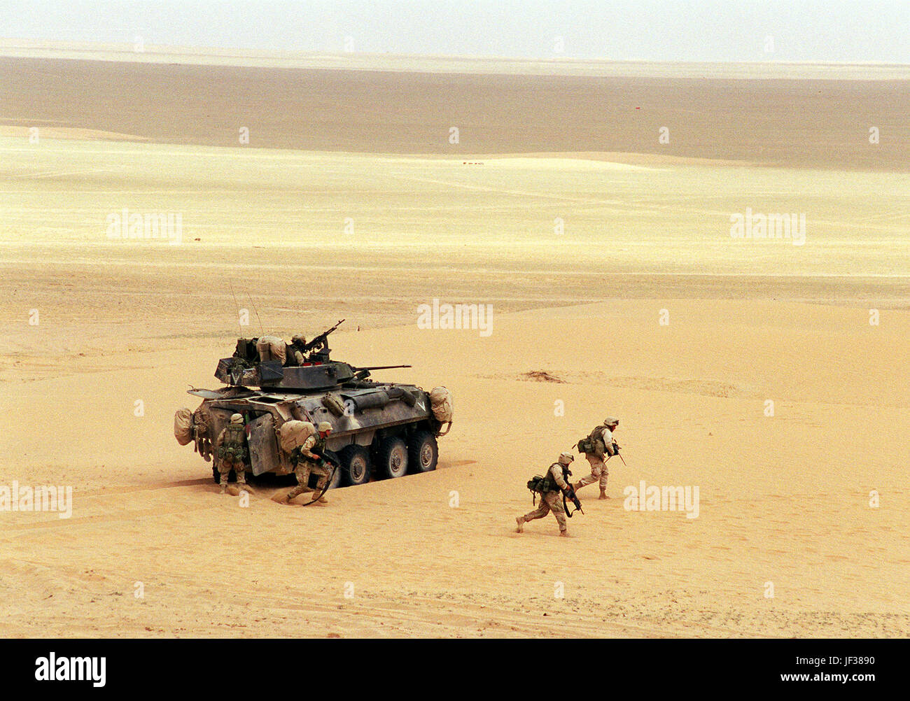 000408-D-9880W-104 U.S. Marine Corps riflemen deploy from a Light Armored Vehicle (LAV-25) during a live-fire training exercise at the Udairi Training Range in northern Kuwait on April 8, 2000.  After destroying the simulated enemy trucks with its turret-mounted 25 mm chain guns, the LAV deployed six Marine riflemen to deal with the remaining simulated enemy personnel.  The LAV is attached to the 1st Light Armored Reconnaissance Battalion, 15th Marine Expeditionary Unit.  DoD photo by R. D. Ward.  (Released) Stock Photo