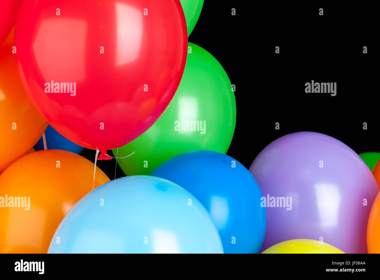 Colorful rubber balloons over black wall background Stock Photo