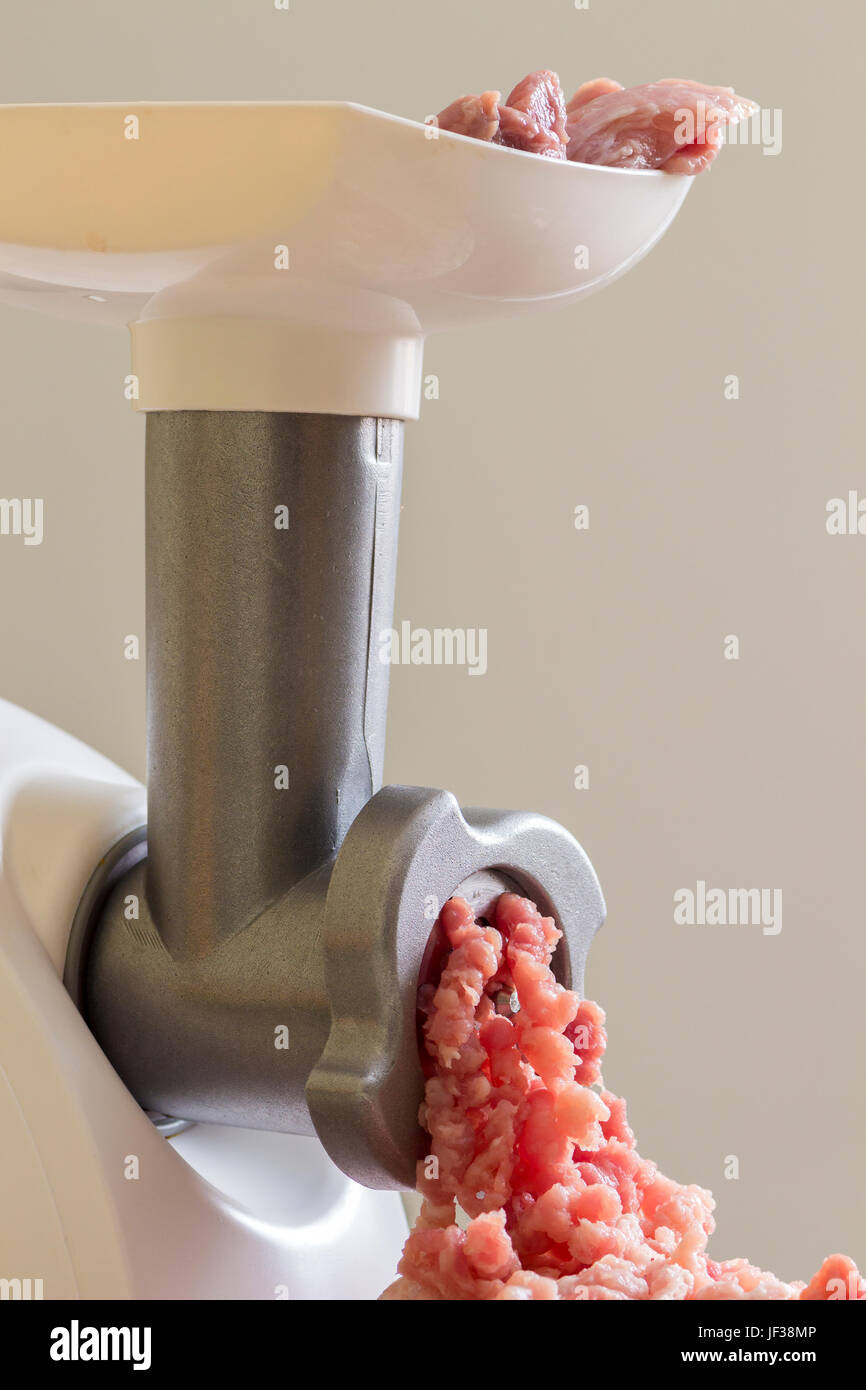 Raw meat is scrolled through a meat grinder closeup Stock Photo Alamy