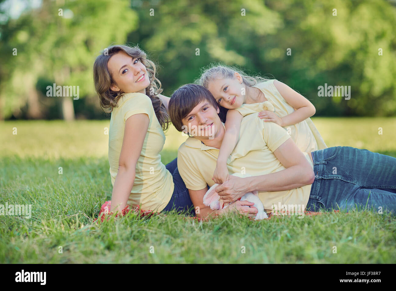 Happy family lying on grass in park Stock Photo - Alamy