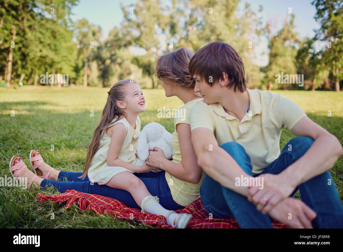 Happy family playing in the park sitting on grass in summer Stock Photo ...