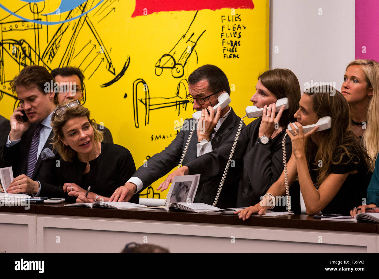 London, UK. 28 June 2017. Sotheby's staff taking telephone bids from cliients in front of Andy Warhol and Jean-Michel Basquiat's, Sweet Pungent, 1984–85, which sold for GBP 4,433,750. Sotheby’s Contemporary Art Evening Auction takes place at their New Bond Street premises. Stock Photo