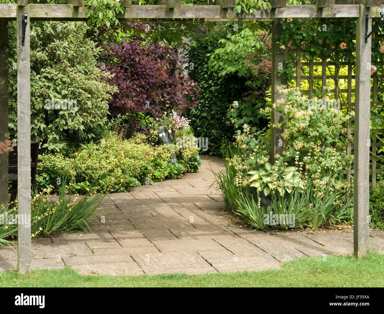 Slabbed patio and path with wooden pergola and trellis, Barnsdale Gardens, Oakham, Rutland, UK Stock Photo