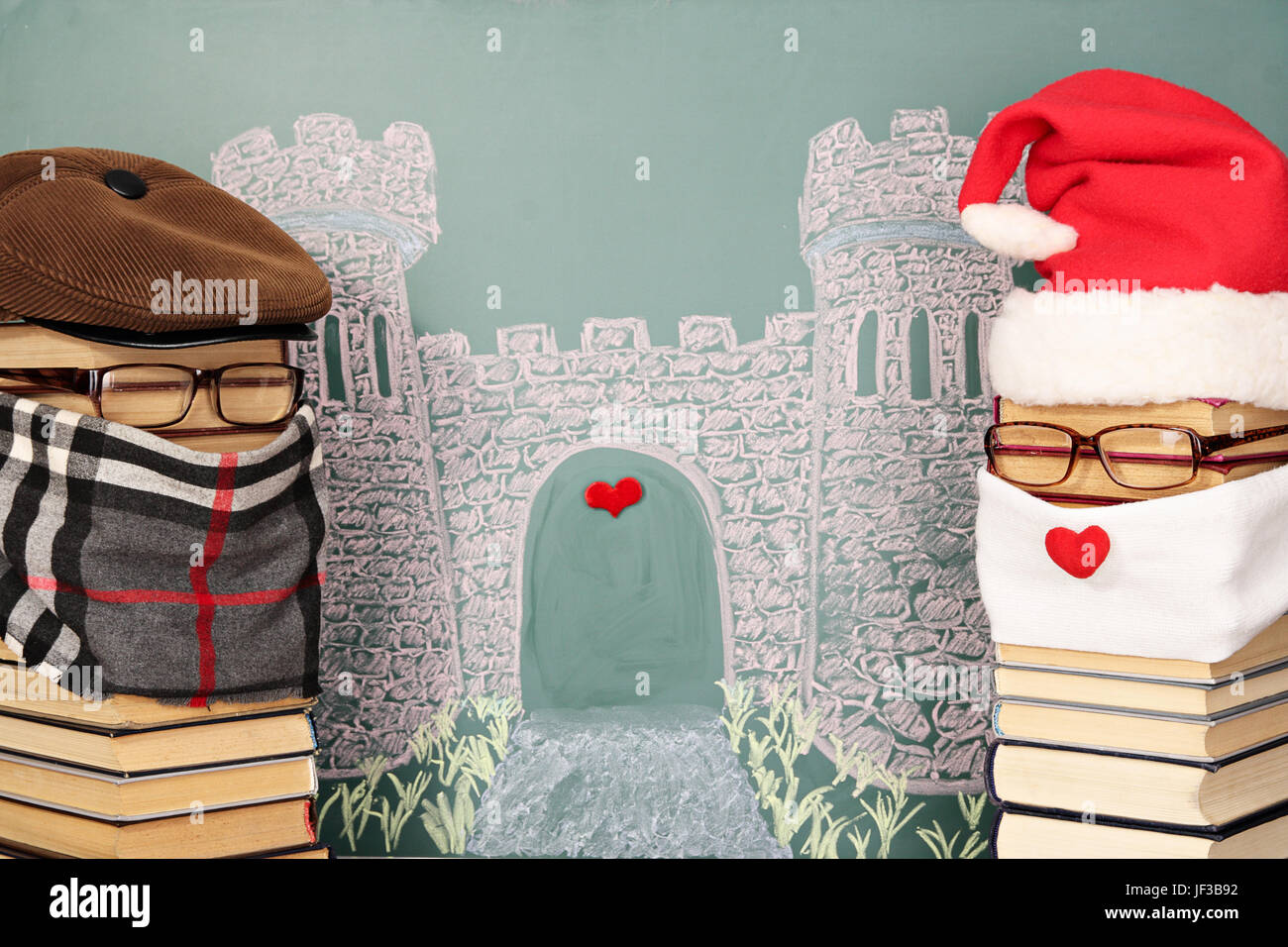 Unusual Santa Claus and author of story from books before blackboard with drawing chalk of castle Stock Photo