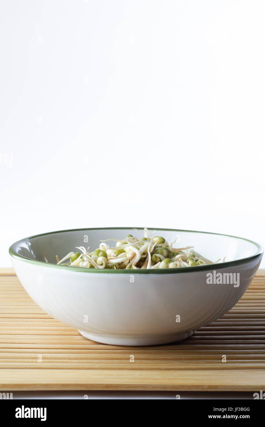 A bowl of mung beansprouts on a bamboo placemat with copy space above.  Portrait (vertiical) orientation. Stock Photo