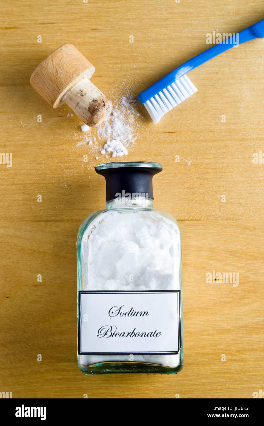 A toothbrush and a bottle of Sodium Bicarbonate (baking soda) laid flat ...