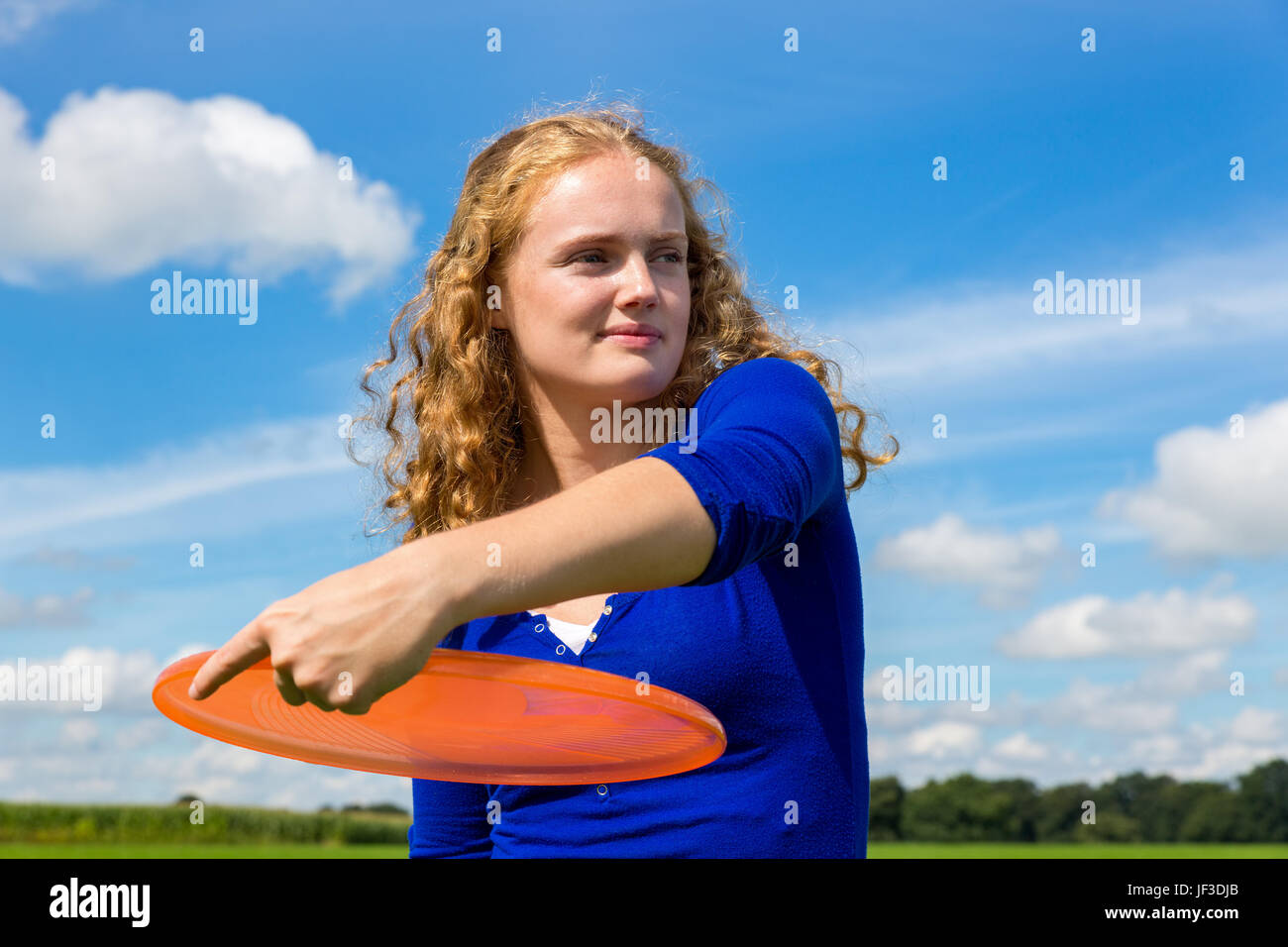 Young dutch woman throwing orange frisbee Stock Photo