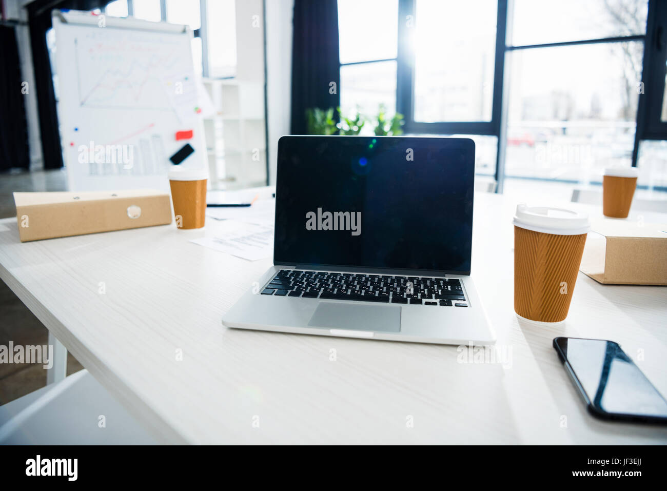 laptop computer, smartphone and coffee cups on workplace in empty ...