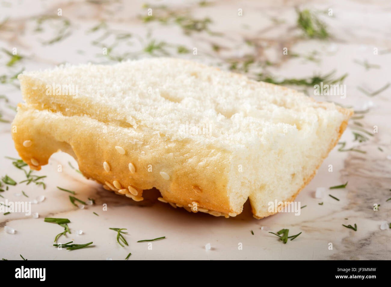 Slice of fresh baguette with sesame on table with herbs and sea salt Stock Photo