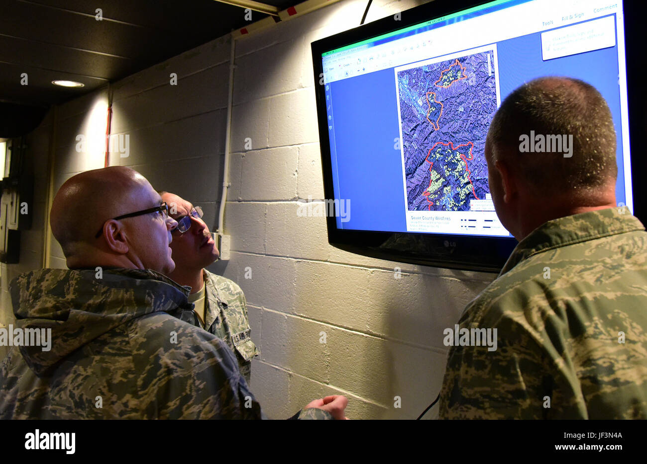 Tech. Sgt. Daron, a member of the 236th Intelligence Support, shows two airmen a map of the fires in east Tennessee on Jan. 7, 2017 a Berry Field Air National Guard base in Nashville, TN. The 236th IS provided valuable imagery and mapping support to the Tennessee Emergency Management Agency and other civilian agencies fighting the fires. (U.S. Air National Guard photo by Senior Airman Anthony Agosti) Stock Photo