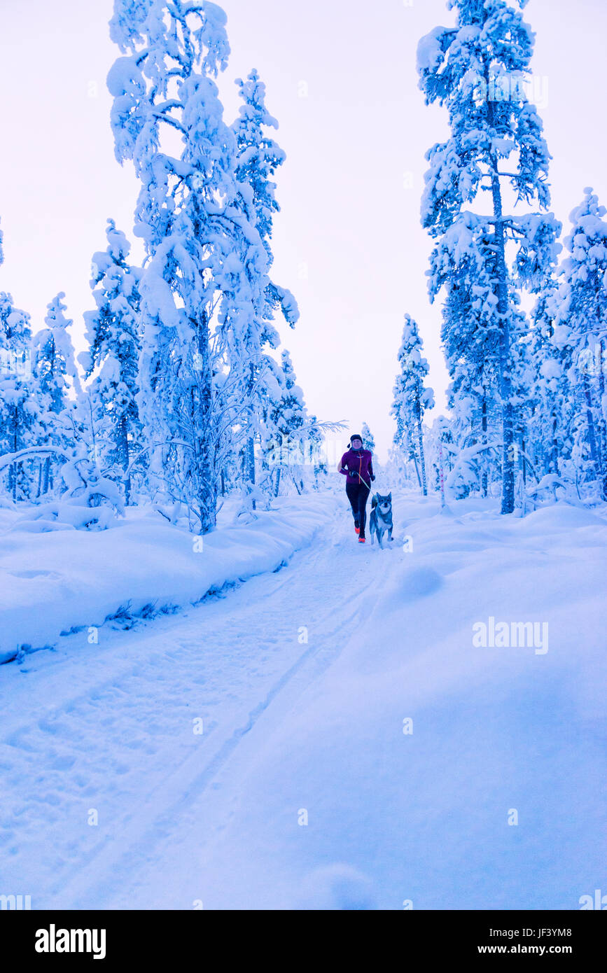 Woman running with dog at winter Stock Photo