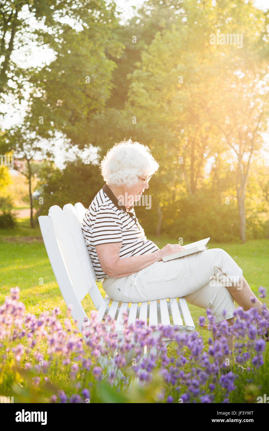 Senior woman reading book in garden Stock Photo - Alamy