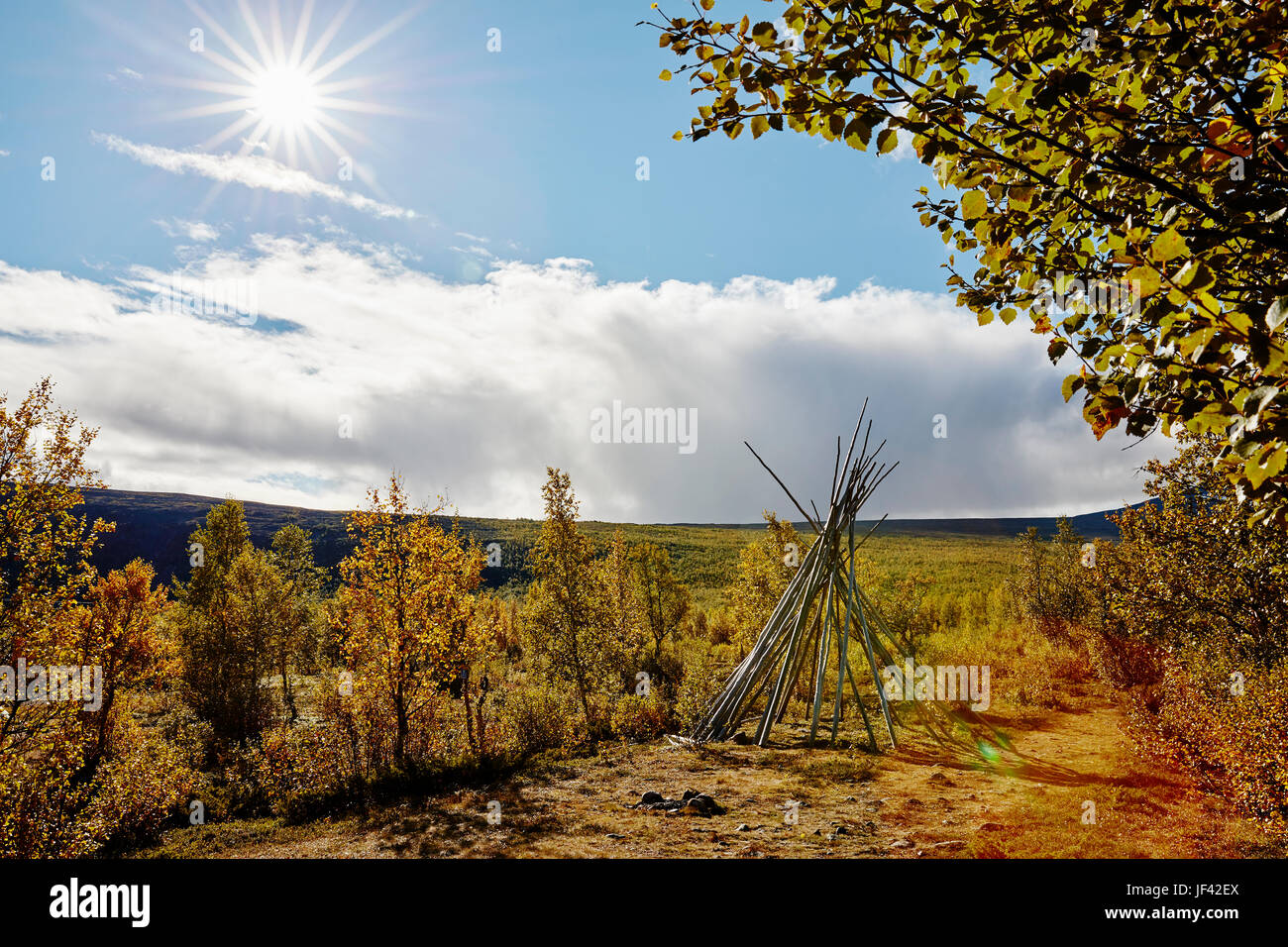 Autumn landscape with teepee-shaped log structure in foreground Stock Photo