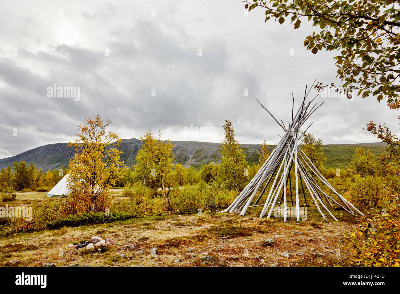 Autumn landscape with teepee-shaped log structure in foreground Stock Photo