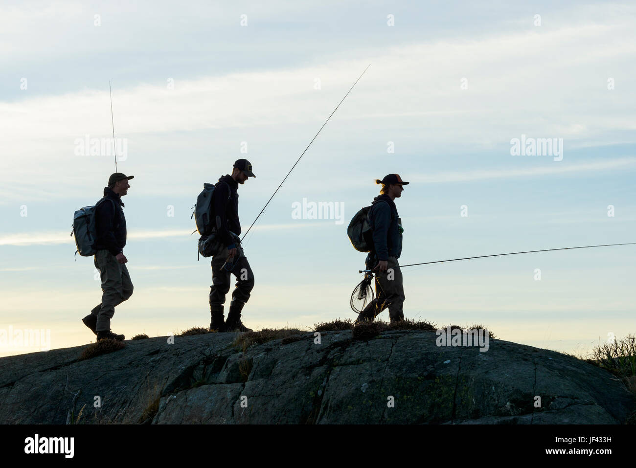 Men with fishing rods walking on coast Stock Photo - Alamy