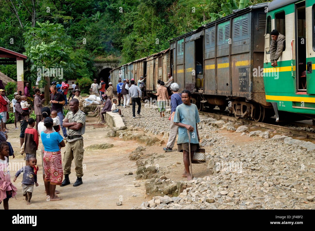 Travellers and local people wait at the side of the tracks during one of the 18 stops on the Fianarantsoa-Côte Est Railway which runs between Fianaran Stock Photo