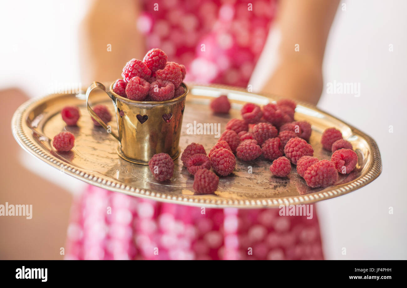 Woman holding a cup of raspberries Stock Photo - Alamy