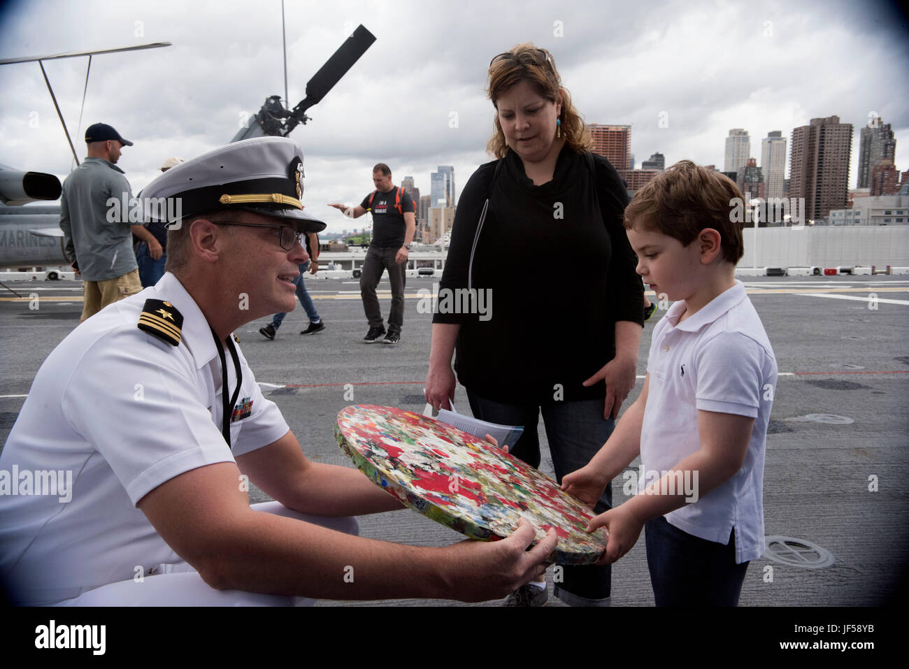 170526-N-MS174-002 NEW YORK (May 26, 2017) Lt. Cmdr. James McLeod, a public affairs officer assigned to U.S. Fleet Forces Command, shows a shipboard-generated compressed plastic disk to a child at the U.S. Navy’s “Stewards of the Sea: Defending Freedom, Protecting the Environment” exhibit aboard the amphibious assault ship USS Kearsarge (LHD 3) during Fleet Week New York. The Navy employs every means available to mitigate the potential environmental effects of our activities without jeopardizing the safety of our Sailors or impacting our Navy readiness mission. (U.S. Navy photo by Bobbie A. Ca Stock Photo