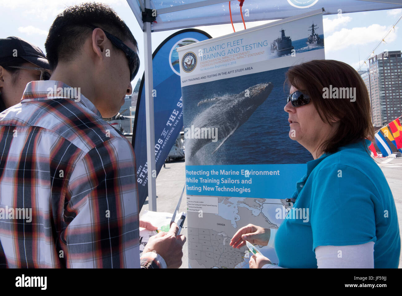 170527-N-MS174-001 NEW YORK (May 27, 2017) Laura Busch, right, a natural resources program manager at U.S. Fleet Forces Command (USFF), discusses the Atlantic Fleet Training and Testing (AFTT) study area with a visitor at the U.S. Navy’s “Stewards of the Sea: Defending Freedom, Protecting the Environment” exhibit aboard the amphibious assault ship USS Kearsarge (LHD 3) during Fleet Week New York. In accordance with the National Environmental Policy Act, USFF is currently in the process of preparing an Environmental Impact Statement to reassess the potential environmental impacts associated wit Stock Photo