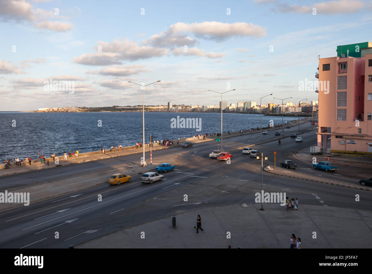 People and traffic move through a large intersection near the Malecon, a promenade along the waterfront in Havana. Stock Photo