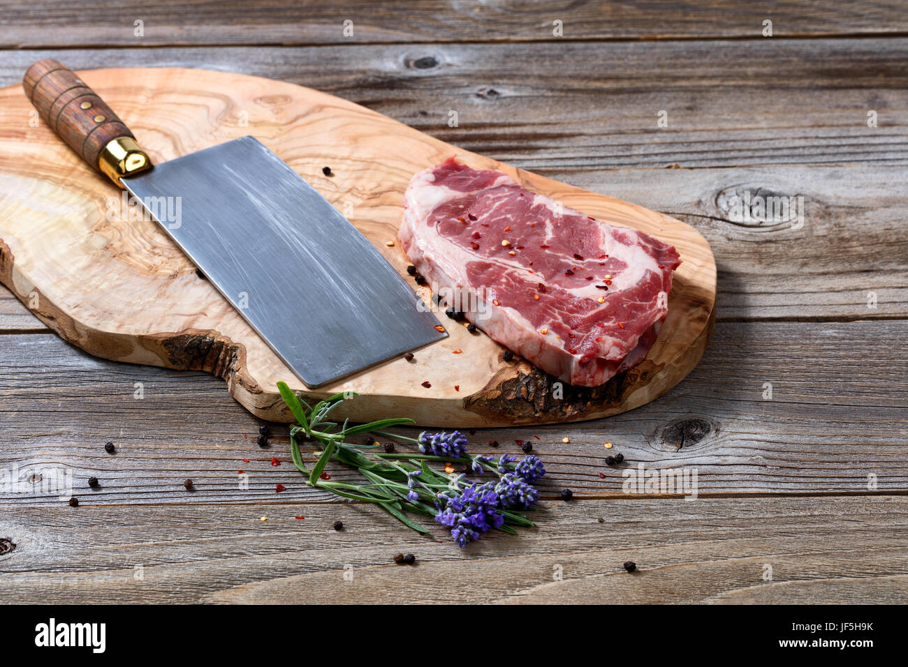 Large butcher knife and raw beef with marbled fat on carving board with ...